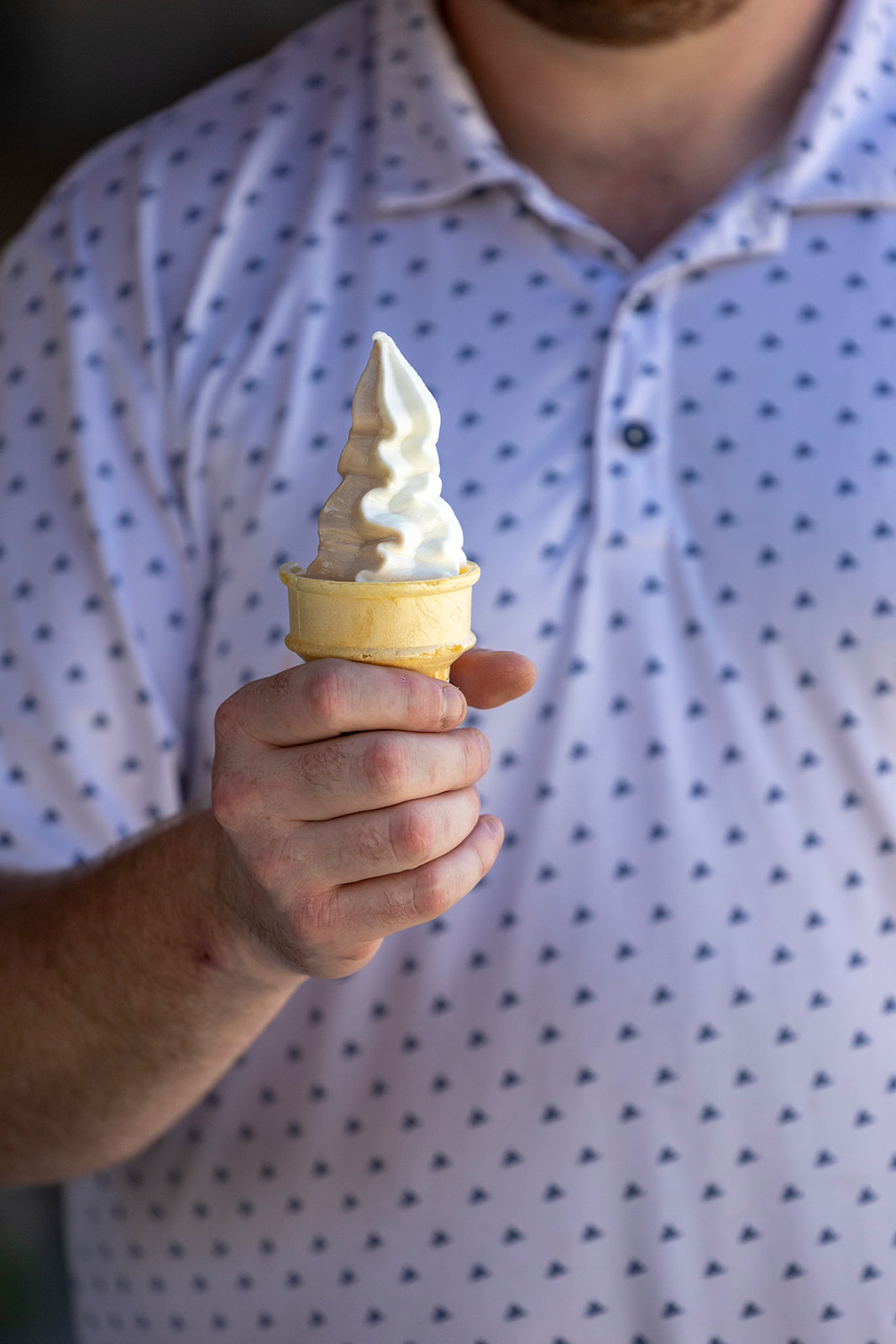 Close-up of a hand holding a soft serve ice cream cone